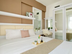 A modern hotel room with a large bed, a desk, a chair, and a sliding door leading to a bathroom. - Comfortable And Decent 2Br At Apartment Kemang View (Bekasi)