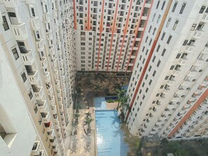 Un edificio residencial de gran altura con varios balcones y un patio central con piscina.