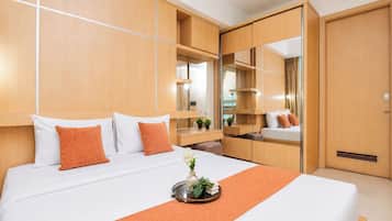 A hotel room with a bed, a bedside table, a mirror, and a wardrobe.