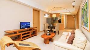 Sala de estar com televisão, sofá, mesa de centro e cadeira de vime.