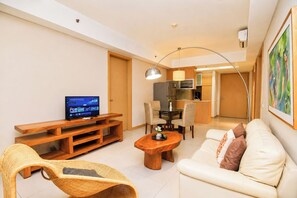 Sala de estar com televisão, sofá, mesa de centro e cadeira de vime.