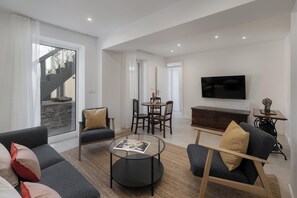 Un salon moderne comprenant un canapé, des fauteuils, une table basse, un téléviseur et un coin repas.