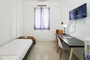 A hotel room with two single beds, a desk with a chair, a television mounted on the wall, and a window with curtains. - Comfy And Nice Studio (No Kitchen) At Apartment Kubikahomy (Pagedangan)