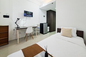 Ein Hotelzimmer mit Bett, Schreibtisch, Stuhl, Fernseher und Kühlschrank.