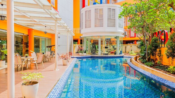 A modern indoor pool area with a clear blue pool, surrounded by lounge chairs and potted plants. - Comfy And Nice Studio (No Kitchen) At Apartment Kubikahomy (Pagedangan)