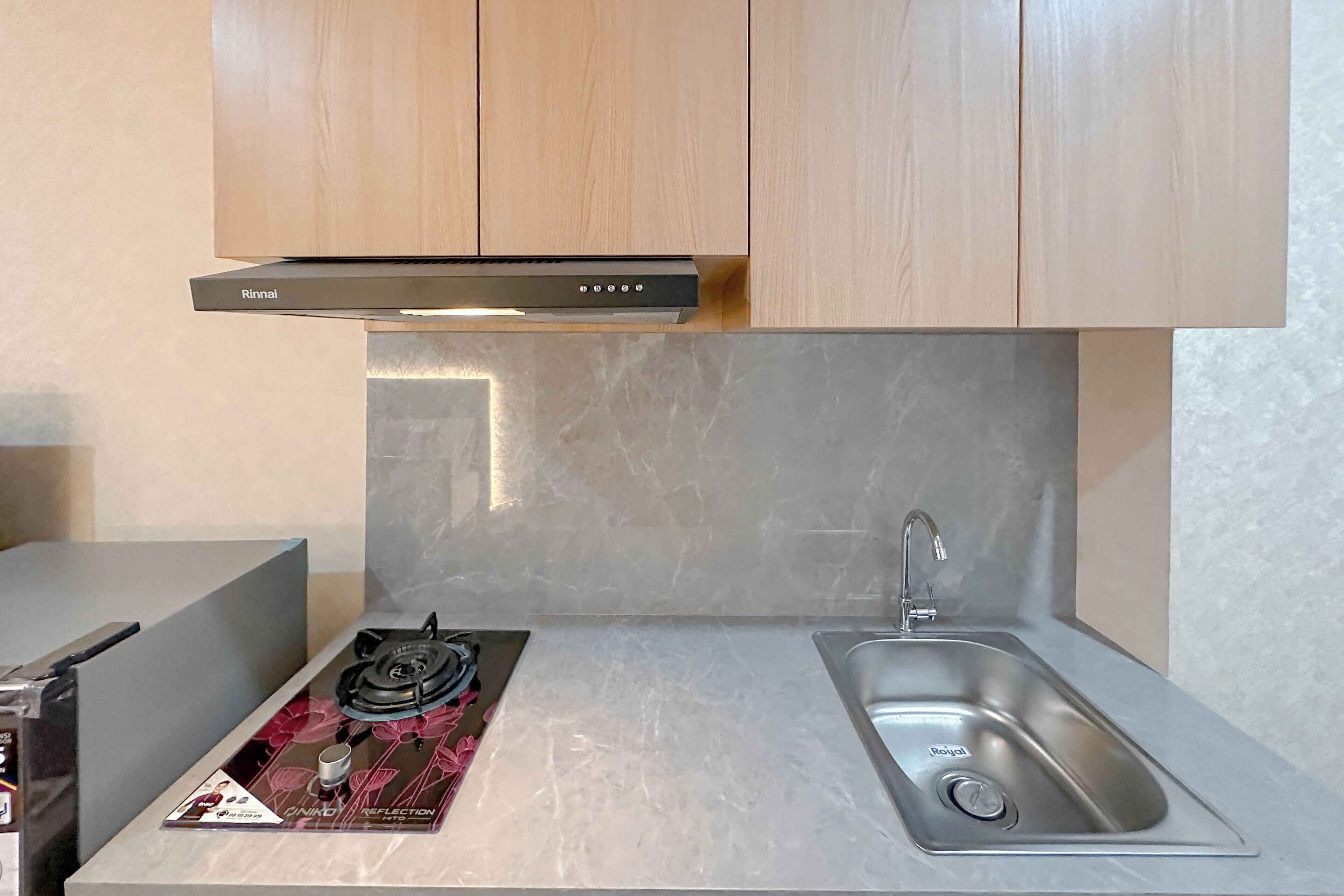 A kitchen with a gas stove, a sink, and wooden cabinets.