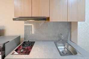 Una cuina amb fogó de gas, un rentat i armaris de fusta.