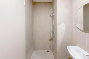 A bathroom with a shower, a sink, and a mirror. - Simple And Chic Studio Near Ubaya At Kyo Society Apartment (Surabaya)