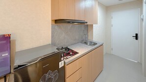 Uma cozinha compacta com fogão embutido, pia, armários de madeira e porta branca.