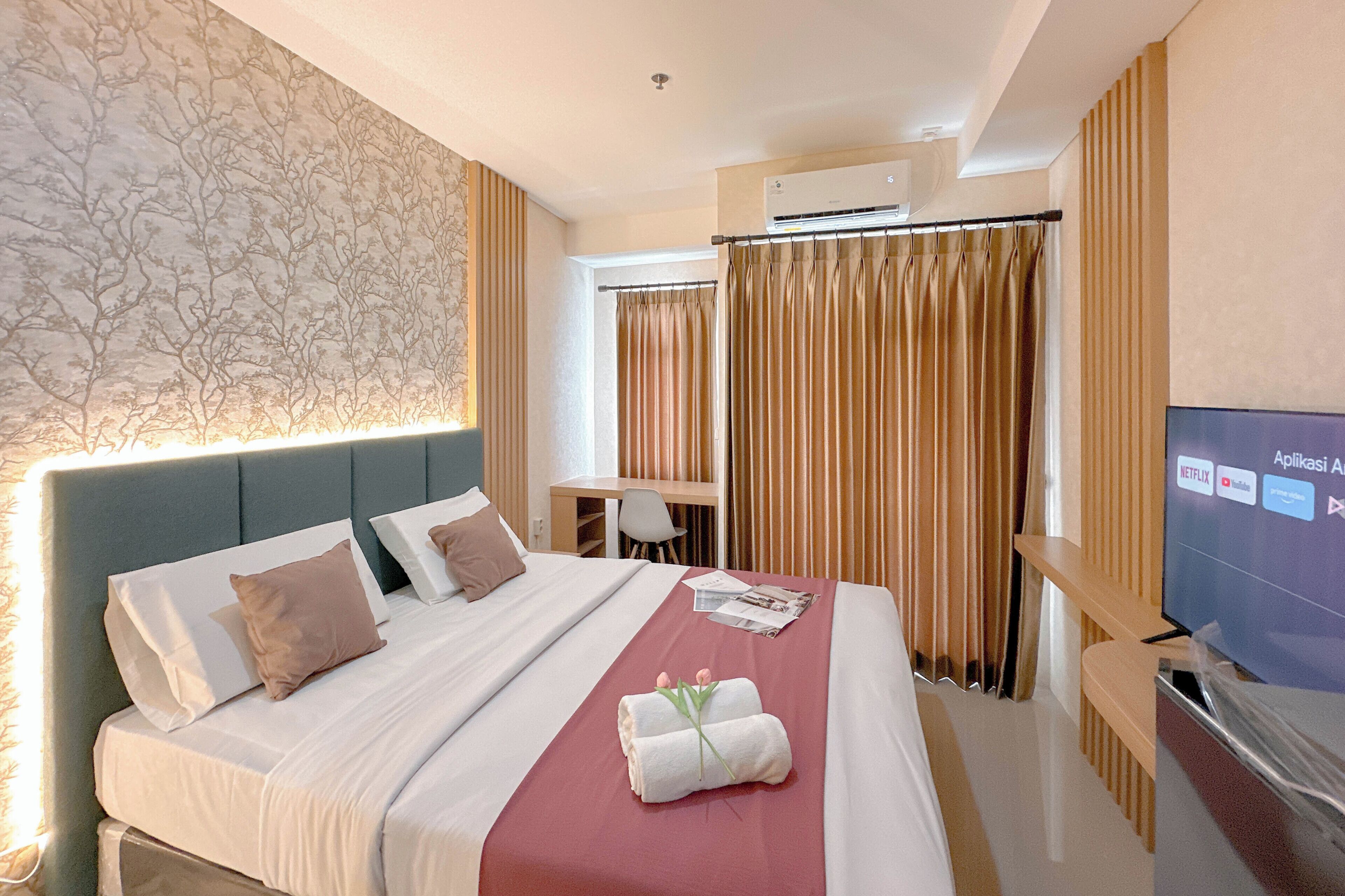 A hotel room with a bed, a desk, a TV, and curtains.