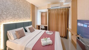 Una habitación de hotel con cama, escritorio, televisor y cortinas.