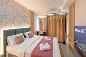 A hotel room with a bed, a desk, a TV, and curtains. - Simple And Chic Studio Near Ubaya At Kyo Society Apartment (Surabaya)