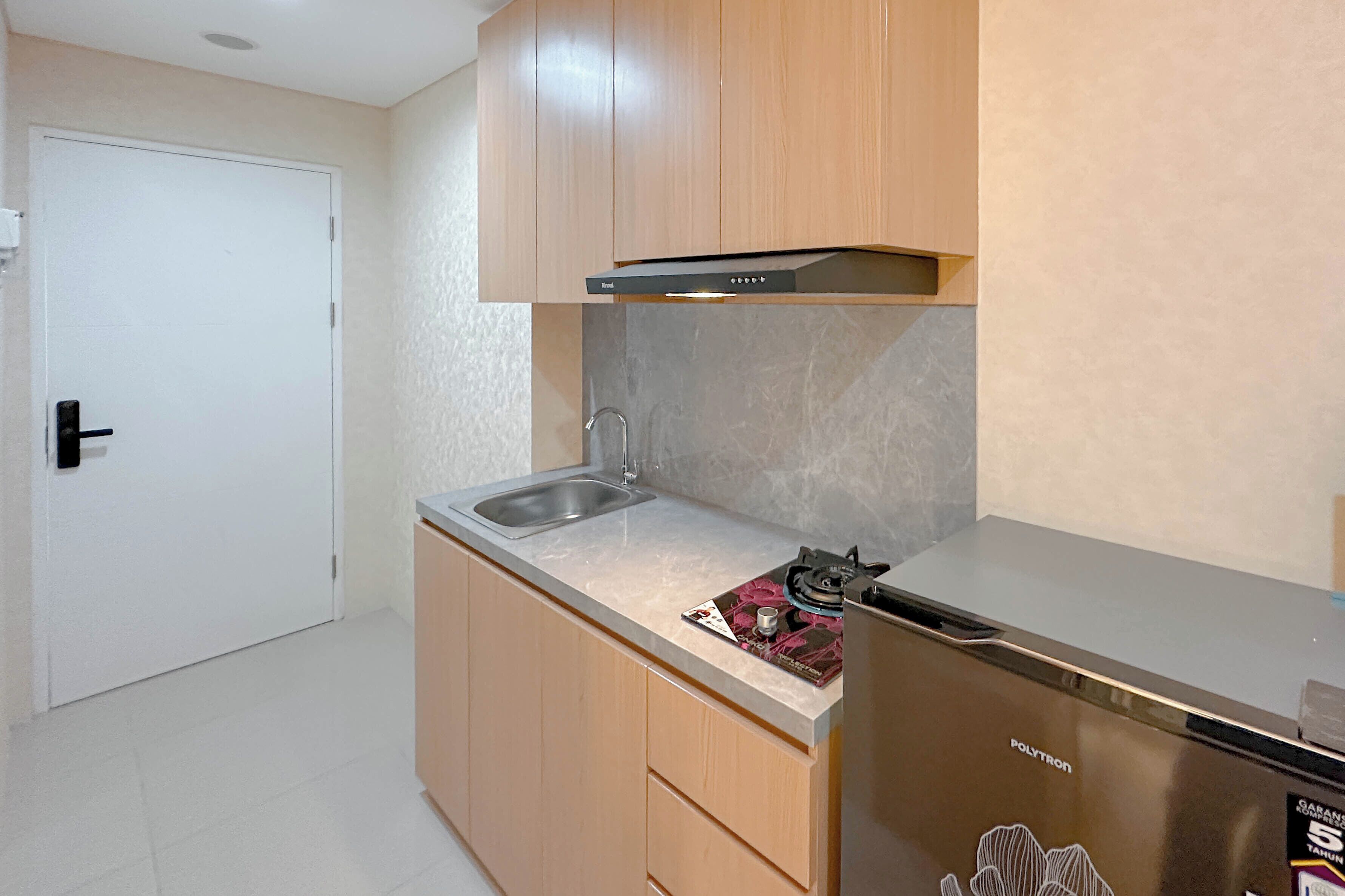 A compact kitchen with a stainless steel refrigerator, a built-in oven, and a sink.