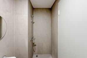 A small, enclosed shower area with a handheld showerhead and a wall-mounted faucet. - Comfy Studio At Kyo Society Apartment (Surabaya)