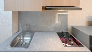 Een keuken met een roestvrijstalen spoelbak, een gasfornuis en een Rinnai afzuigkap.