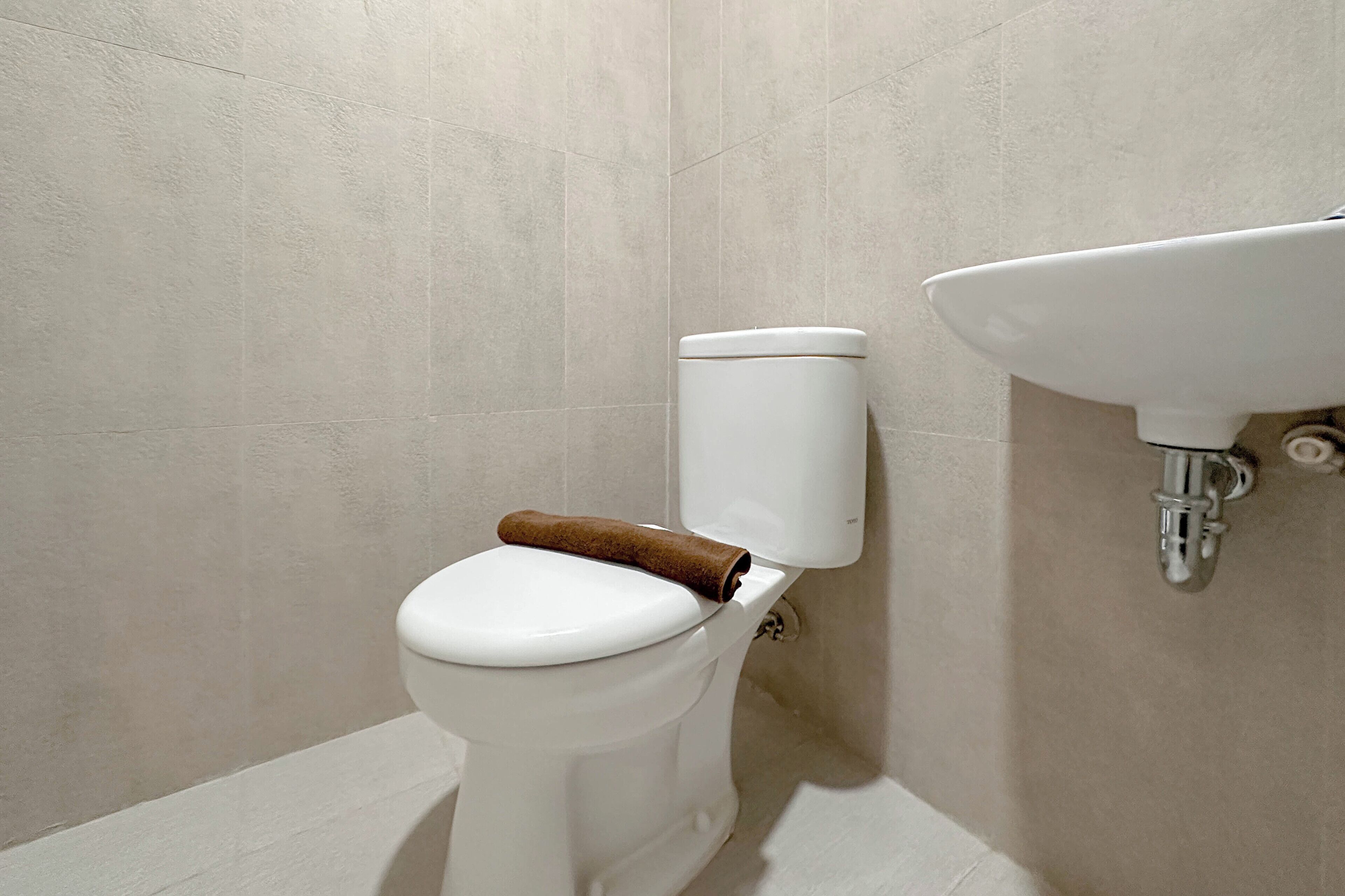 Ein Badezimmer mit Toilette, Waschbecken und gefliesten Wänden.
