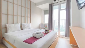 Ein Hotelzimmer mit Bett, Schreibtisch, einem Fenster mit Vorhängen und Blick auf die Stadt.