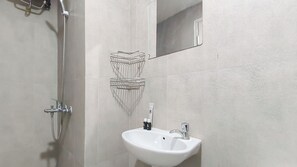 A bathroom with a shower, a sink, and a mirror. - Zen Style Studio At Kyo Society Apartment (Surabaya)