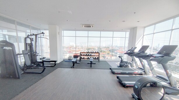 A gym with treadmills, elliptical machines, and weight equipment. - Zen Style Studio At Kyo Society Apartment (Surabaya)