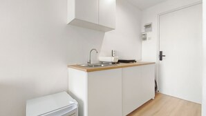 A compact kitchen with a sink, countertop, and cabinets. - Zen Style Studio At Kyo Society Apartment (Surabaya)
