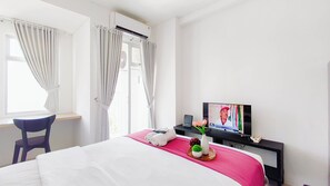 Ein Hotelzimmer mit Bett, Schreibtisch, Fernseher und einem Fenster mit Vorhängen.
