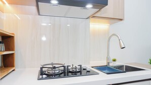 A modern kitchen with a gas stove, a stainless steel sink, and a built-in oven. - 2 Pax Serene Studio At Lrt City Bekasi Apartment (Bekasi)