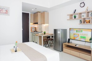 Ein modernes Zimmer mit einem Bett, einem Fernseher, einer Küchenzeile und einer kleinen Sitzecke.