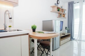 Eine moderne Küche mit integriertem Spülbecken, einem Edelstahlkühlschrank, einem Holztisch und einem kleinen Topfpflanzen.