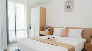 A hotel room with a bed, a nightstand, a desk, a chair, a window with curtains, and a wall-mounted picture. - 2 Pax Serene Studio At Lrt City Bekasi Apartment (Bekasi)