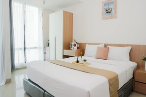A hotel room with a bed, a nightstand, a desk, a chair, a window with curtains, and a wall-mounted picture. - 2 Pax Serene Studio At Lrt City Bekasi Apartment (Bekasi)
