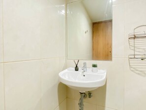 Ein Badezimmer mit einem weißen Waschbecken, einem Spiegel und einer Holztür im Hintergrund.