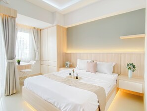 Ein modernes Schlafzimmer mit einem großen Bett, Nachttischen, einem Schreibtisch und einem Sessel.