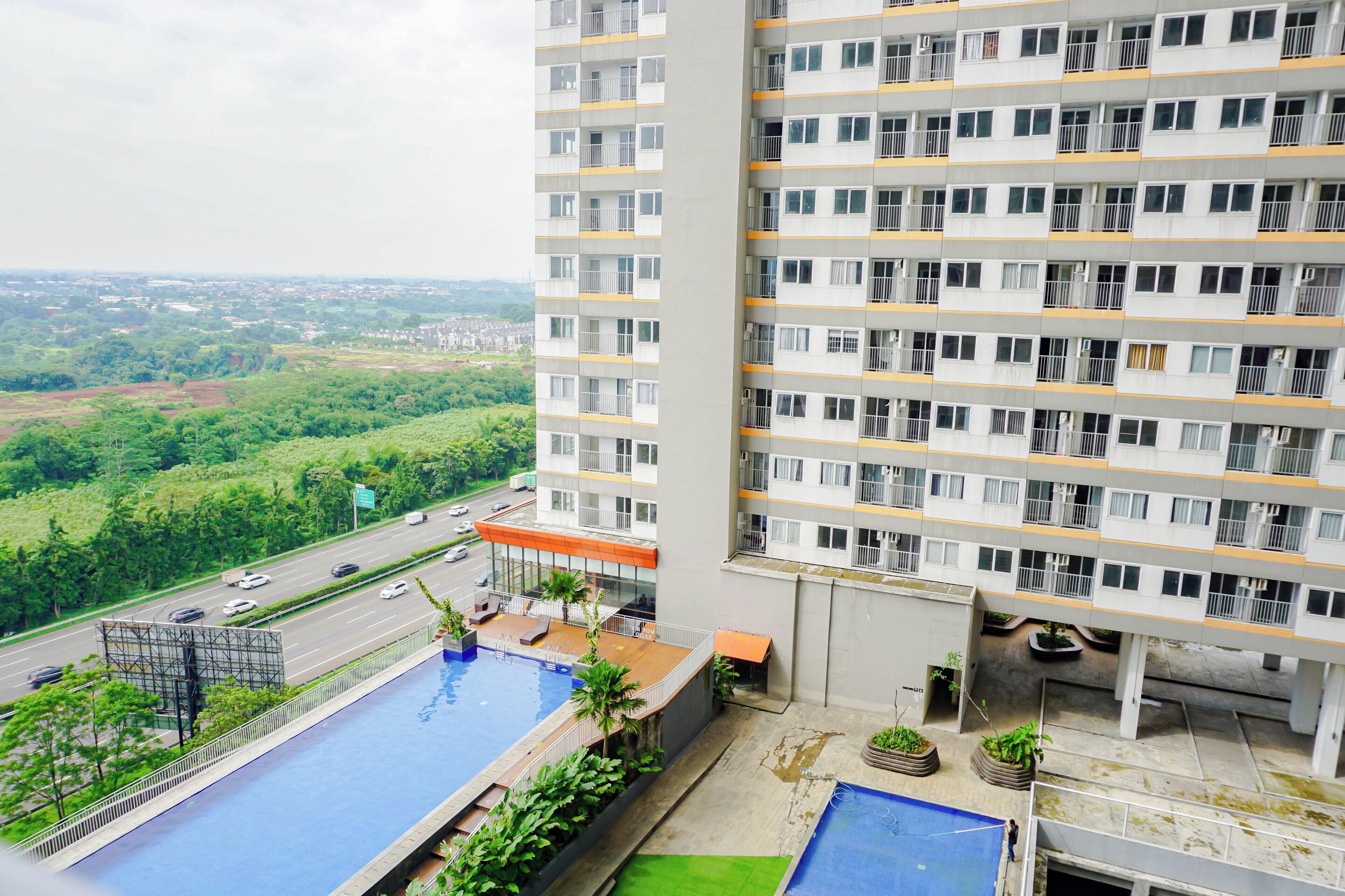 Un edificio alto con varios balcones, piscina y vistas a un paisaje verde.