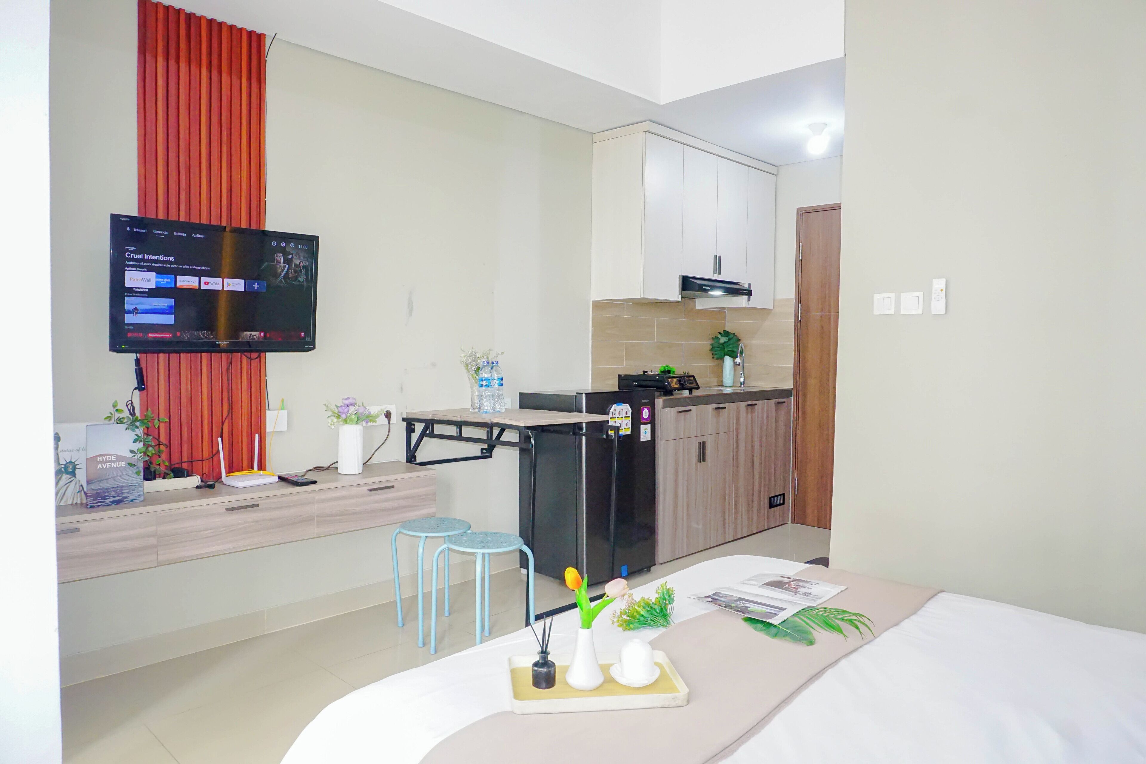 Une chambre d’hôtel moderne équipée d’un lit, d’un bureau avec un ordinateur, d’une télévision et d’une kitchenette.