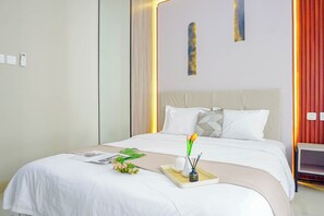 Ein ordentlich bezogenes Bett mit weißer Bettwäsche, ein Nachttisch mit Lampe und ein Wandbild.