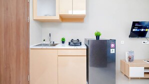 Cocina compacta con refrigerador de acero inoxidable, un lavamanos y una pequeña encimera.