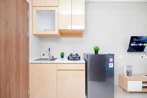 Eine kleine Küche mit einem Edelstahl-Kühlschrank, einer Spüle und einer Arbeitsplatte.