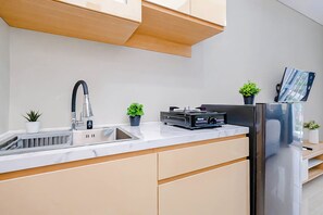 Cozinha moderna com pia de aço inoxidável, fogão embutido e geladeira.