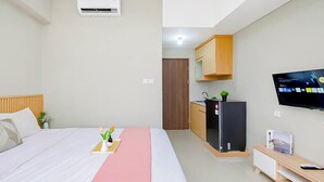 Una habitación de hotel con cama, televisión, kitchenette y un pequeño escritorio.