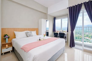 A modern hotel room with a large bed, a desk, and a view of the city.