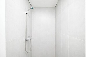 Eine Dusche mit Handbrause und Wandarmatur in einem gefliesten Raum.