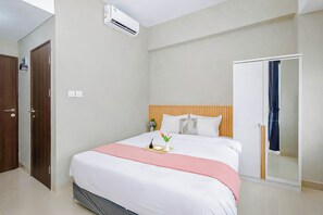 Ein Hotelzimmer mit Bett, Nachttisch, Kleiderschrank und Beistelltisch.