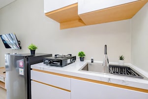 A modern kitchen with a built-in refrigerator, a sink, a small island, and a flat-screen TV mounted on the wall.