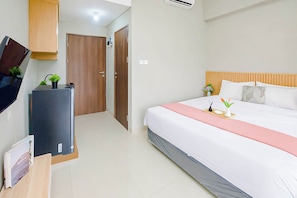 Una habitación de hotel con cama, televisión, escritorio y armario.