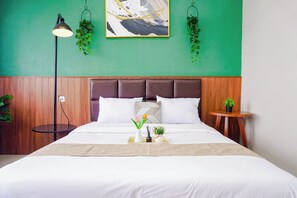 Ein ordentlich bezogenes Bett mit weißen Leinen, ein Kopfteil mit geometrischem Muster und ein Nachttisch mit einer kleinen Pflanze.
