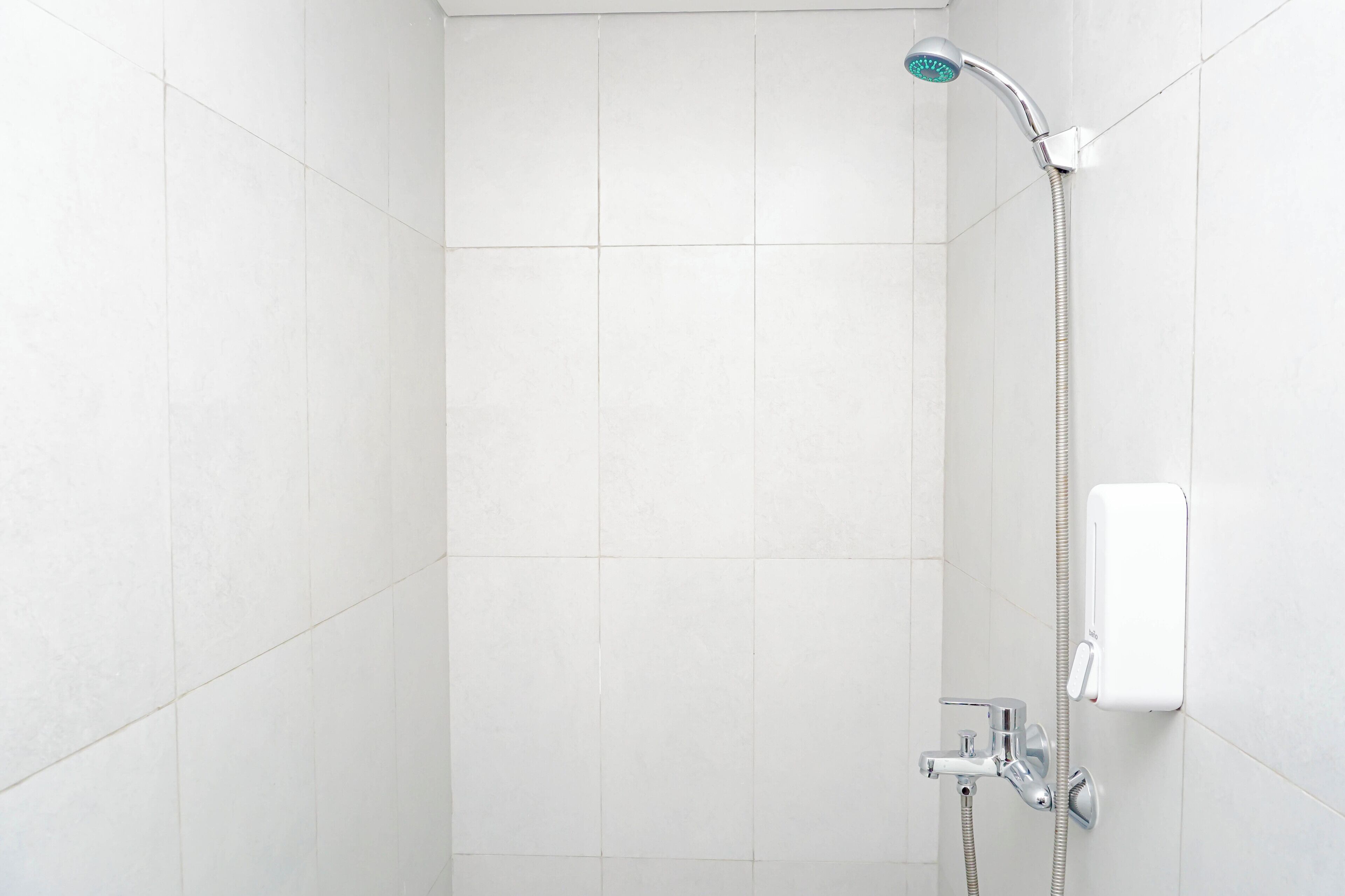 Ducha con cabezal de ducha de mano y panel de control en la pared.