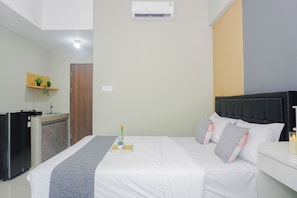 Ein Hotelzimmer mit Bett, Nachttisch und einer kleinen Küchenzeile.