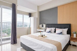 A modern hotel room with a large bed, a desk, a chair, and a view of the city. - Comfortable Living Studio At Apartment Lrt City Sentul - Royal Sentul Park (Bogor)