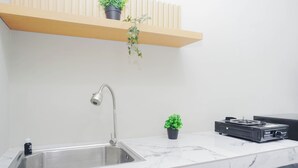 Una cocina con un lavabo, un grifo, una encimera, una estufa y dos plantas en macetas.
