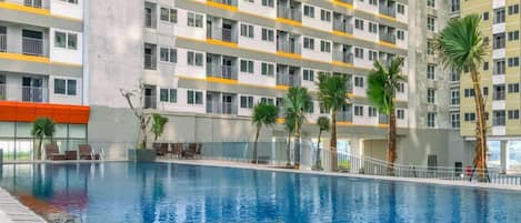 Piscina com um edifício moderno ao fundo.